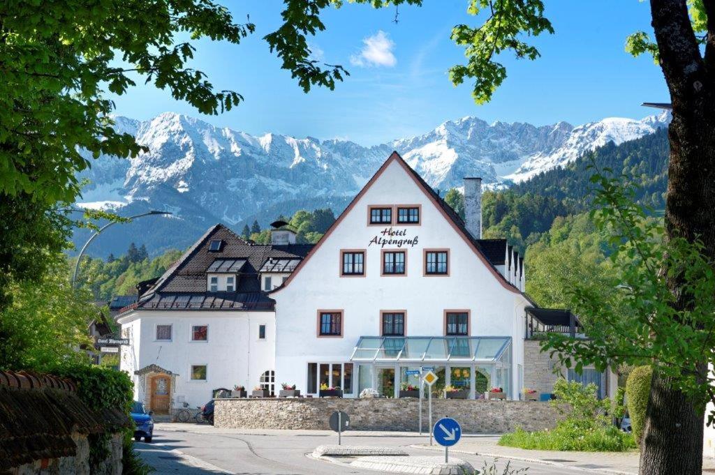 ein großes weißes Gebäude mit Bergen im Hintergrund in der Unterkunft Hotel garni Alpengruss in Garmisch-Partenkirchen