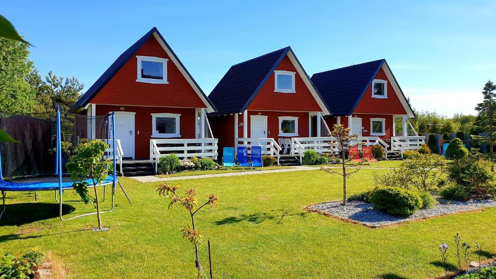 ウストカにあるDomki Letniskowe Skandynawiaの庭に遊び場がある2棟の赤い家