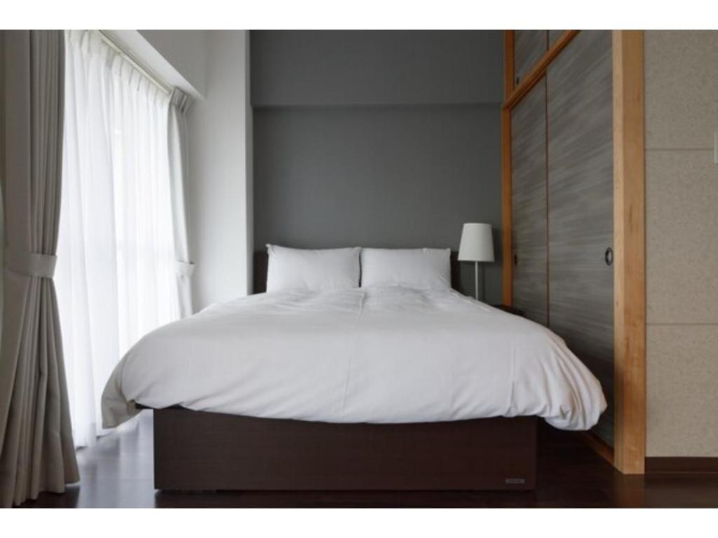 a bedroom with a white bed with a window at WALLABY HOUSE - Vacation STAY 38655v in Kawaguchi