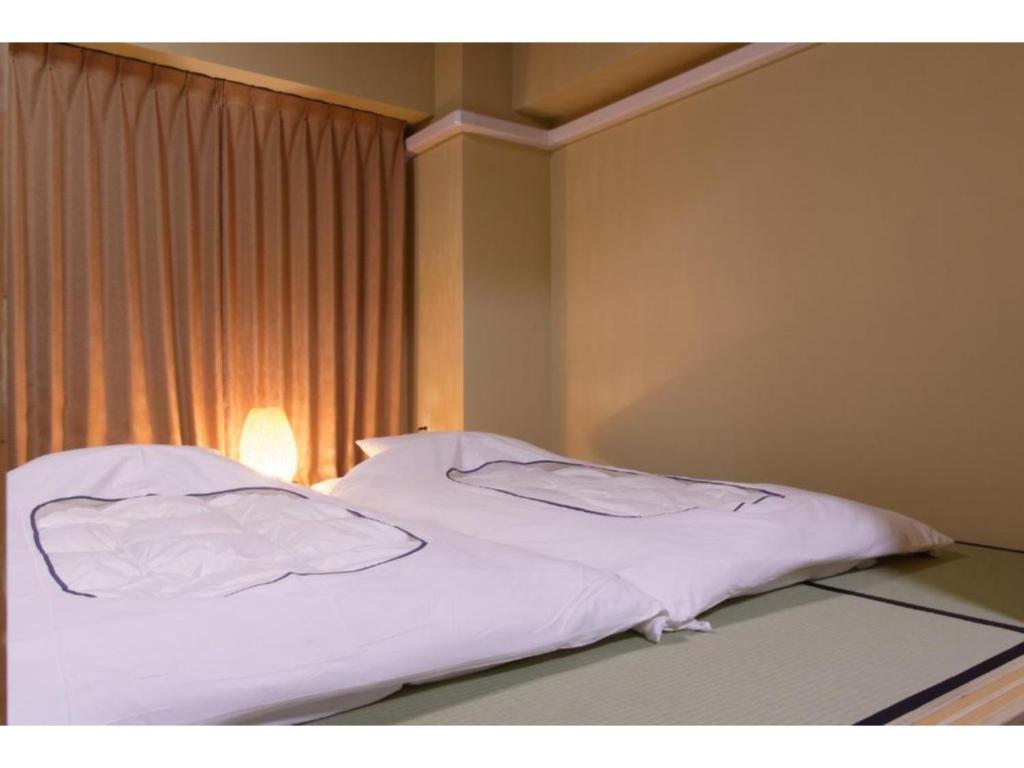 1 cama con sábanas blancas en una habitación con ventana en WALLABY HOUSE - Vacation STAY 38653v en Kawaguchi