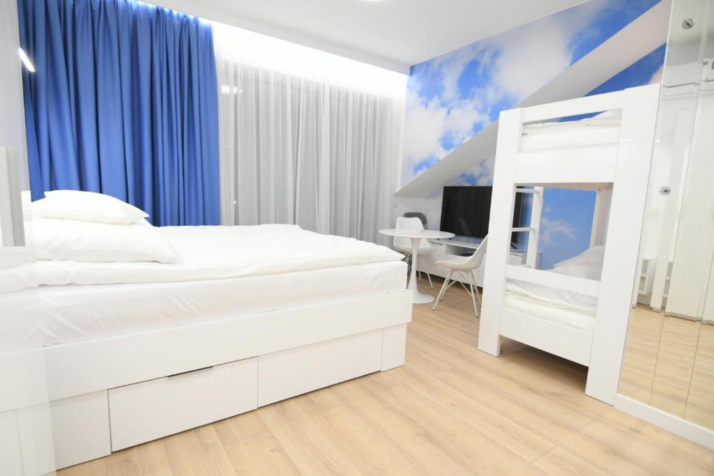 a white bedroom with a bunk bed and a desk at Blue Sky Apartments Rezydencja Niechorze - 302 in Niechorze