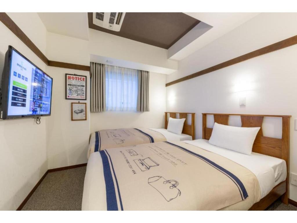 a hotel room with two beds and a flat screen tv at Hotel Emit Shibuya - Vacation STAY 40894v in Tokyo