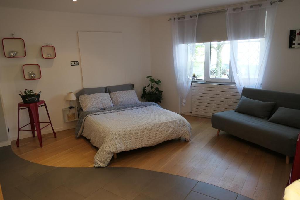 1 dormitorio con cama, sofá y ventana en Au Petit Paradis, en Ammerschwihr