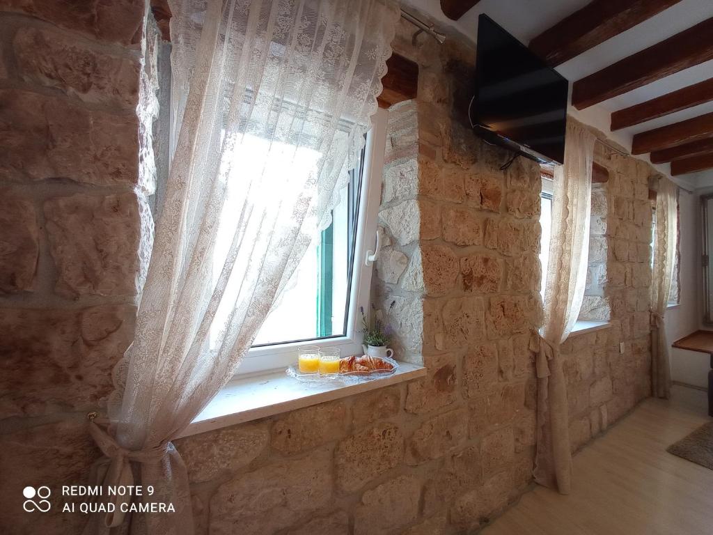 a window with curtains on a stone wall at Studio Makala in Trogir