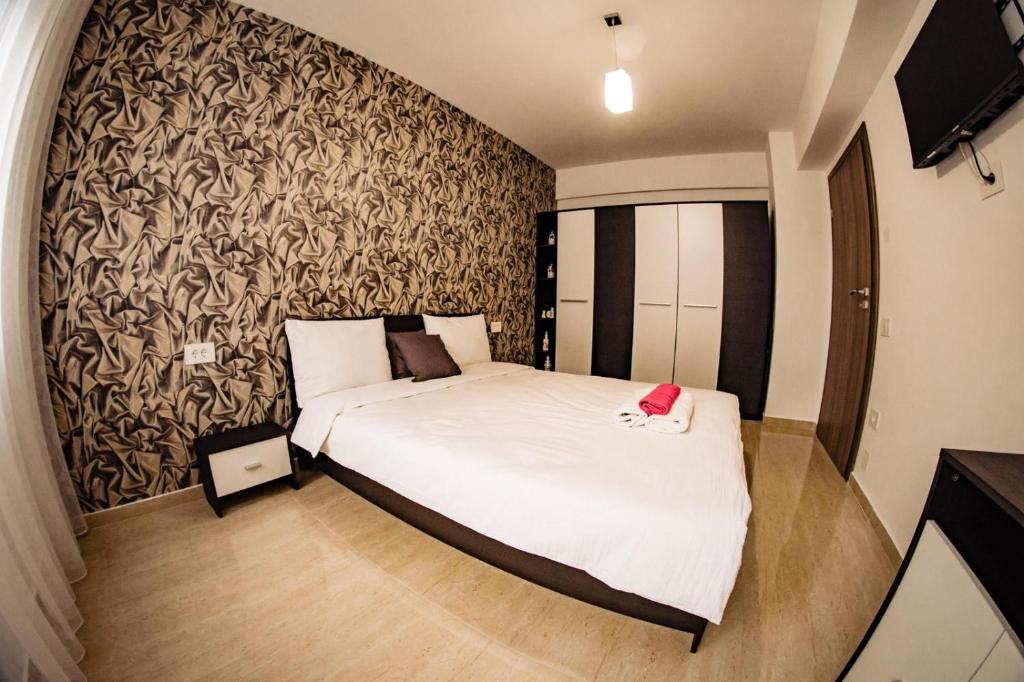 ein Schlafzimmer mit einem weißen Bett und einer Wand in der Unterkunft Apartment Gabriela's Home in Oradea