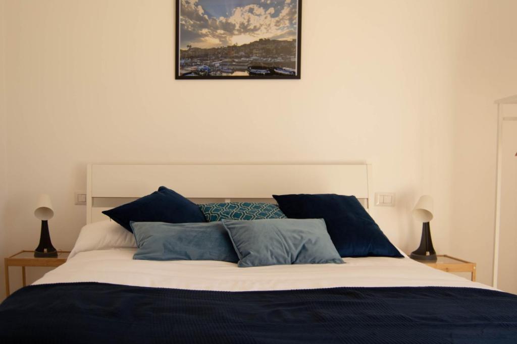 1 cama con almohadas azules y una foto en la pared en Casa Vacanze Caramagna, en Aci Castello
