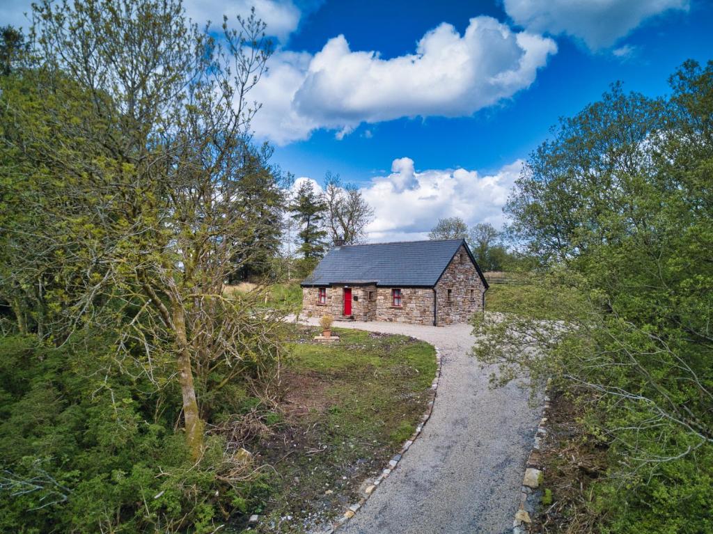 a stone barn with a red door on a road at Glenkeel Cottage in Manorhamilton