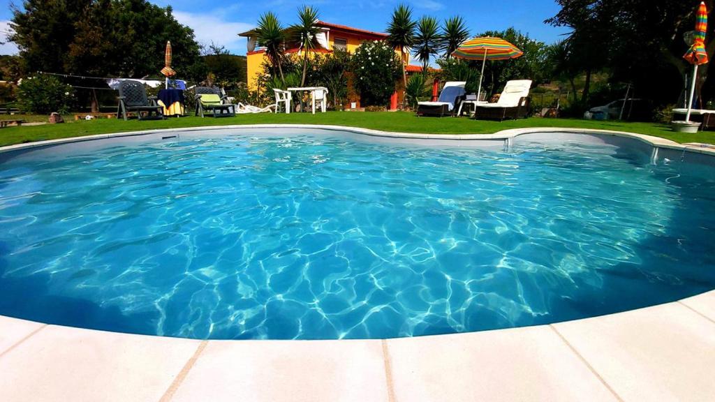 uma grande piscina com água azul num quintal em Bed & Breakfast Il Rosmarino em Bosa