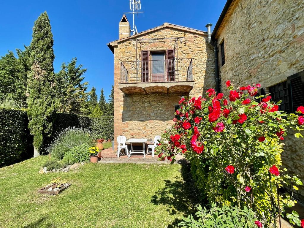 a building with a table and flowers in a yard at Podere Morena with sea view, private garden, by ToscanaTour Luca in Guardistallo