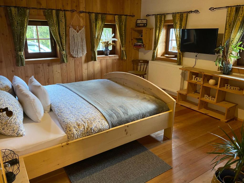 a bedroom with a bed and a tv and windows at Reinwalds Almhütte in Millstatt