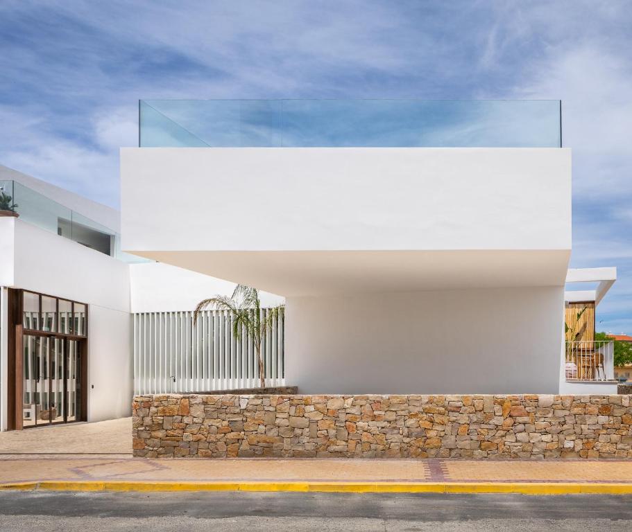 a white building with a stone wall at Hotel Porfirio Picota - Adults Recommended in Zahara de los Atunes