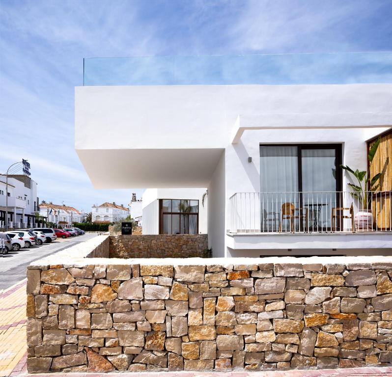 a white house with a stone wall at Hotel Porfirio Picota - Adults Recommended in Zahara de los Atunes
