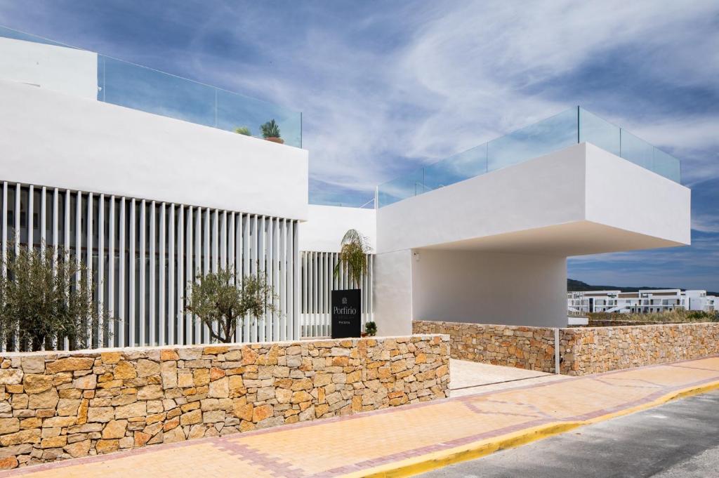 a white building with a stone wall at Hotel Porfirio Picota - Adults Recommended in Zahara de los Atunes