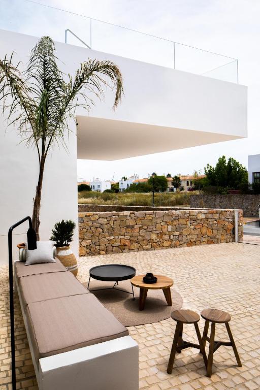 a patio with a couch and two tables and a palm tree at Hotel Porfirio Picota - Adults Recommended in Zahara de los Atunes