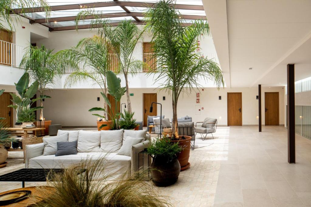 a lobby with a white couch and some plants at Hotel Porfirio Picota - Adults Recommended in Zahara de los Atunes