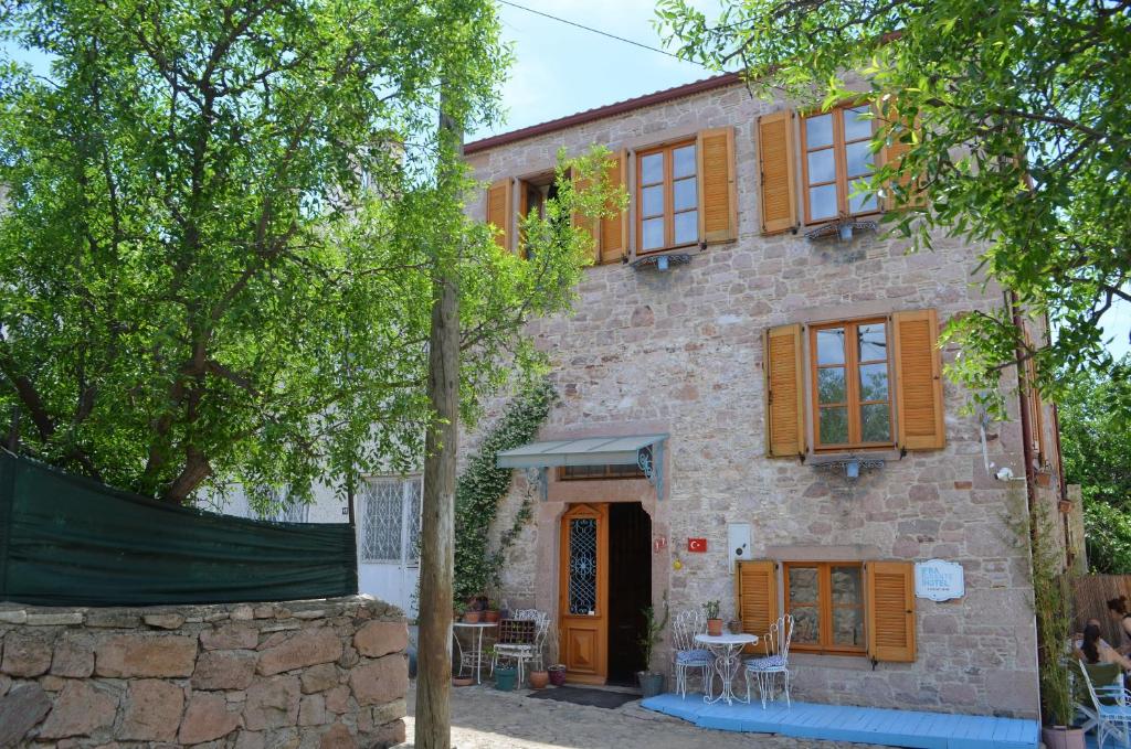 a stone house with wooden shutters and a patio at Fragrante Hotel - Adult Only (+13) in Ayvalık