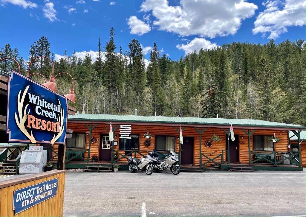 une cabine avec une moto garée devant elle dans l'établissement Whitetail Creek Resort, à Lead