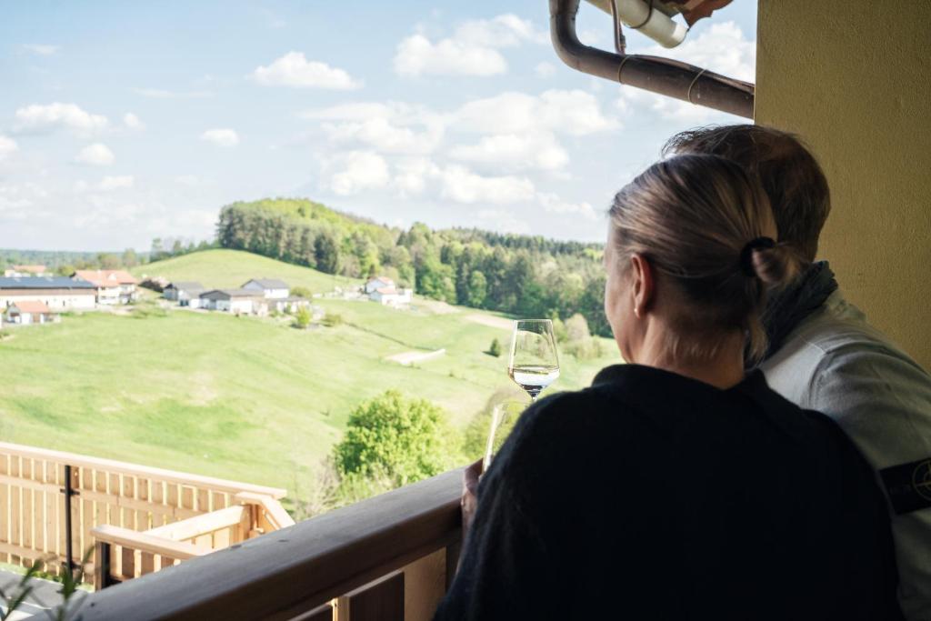 Eine Frau, die aus dem Fenster schaut auf ein grünes Feld in der Unterkunft Kollerwirt in Kapfenstein