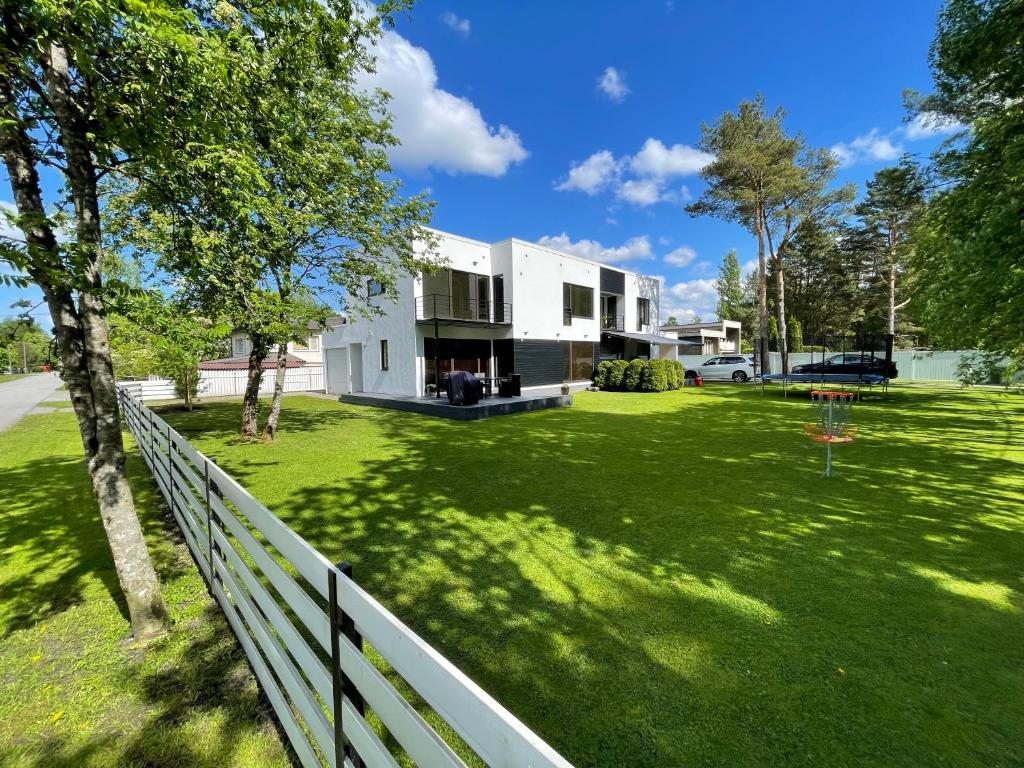 a white house on a green yard with a fence at Pärnu Family House in Pärnu