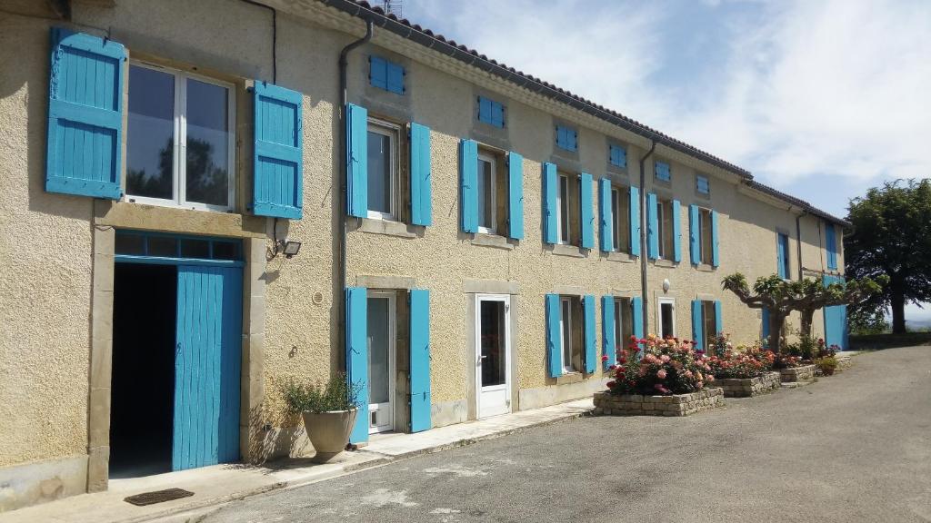 a building with blue shuttered windows and potted plants at La Vigneronne in Villelongue-dʼAude