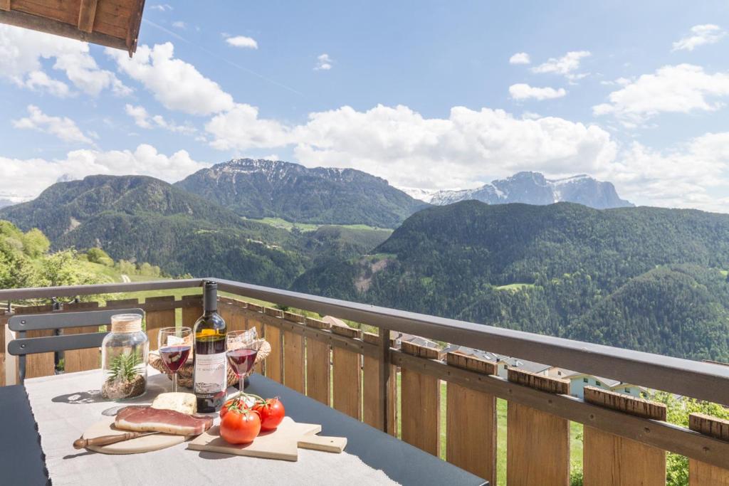 a table with a bottle of wine and tomatoes on a balcony at Apartment La Brunella in Laion