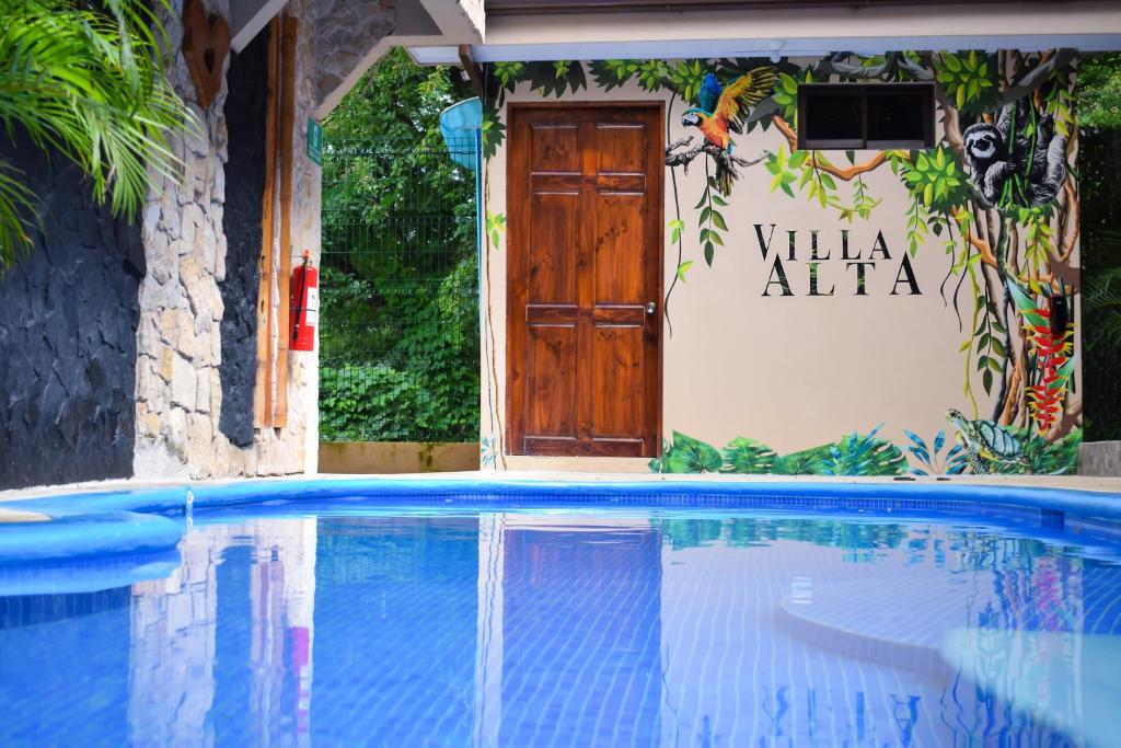 a swimming pool in front of a building with a door at Apartotel VILLA ALTA TAMARINDO in Tamarindo
