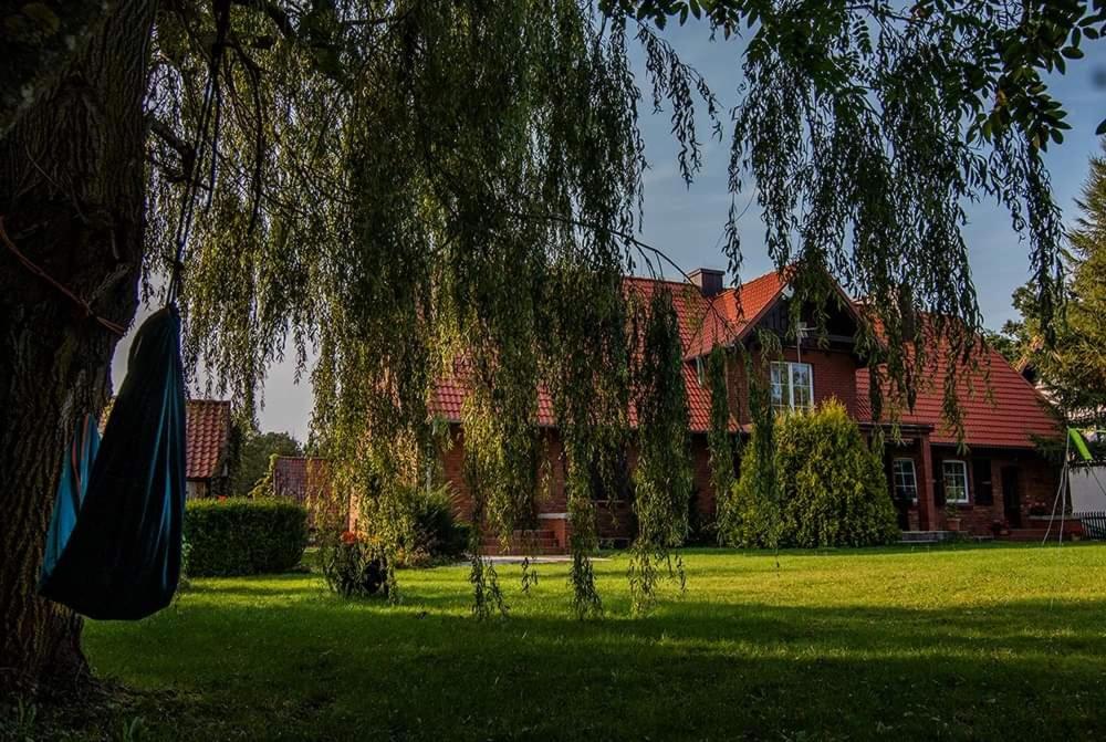 une grande maison avec un arbre en face dans l'établissement Roganty, à Giżycko