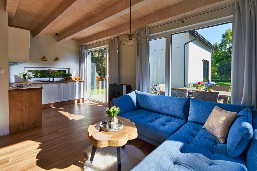 a living room with a blue couch and a table at SosnowoMi - Całoroczne domy na wynajem in Lubiatowo