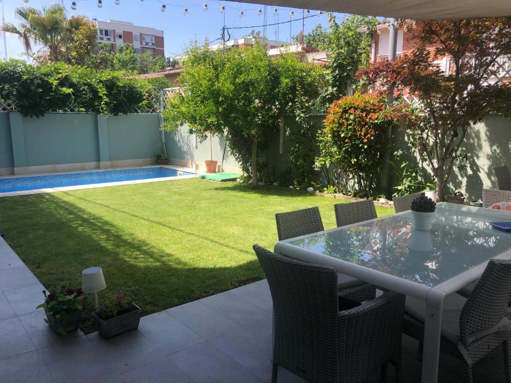 eine Terrasse mit einem Tisch und einem Rasenhof in der Unterkunft chalet villa inside Madrid in Madrid