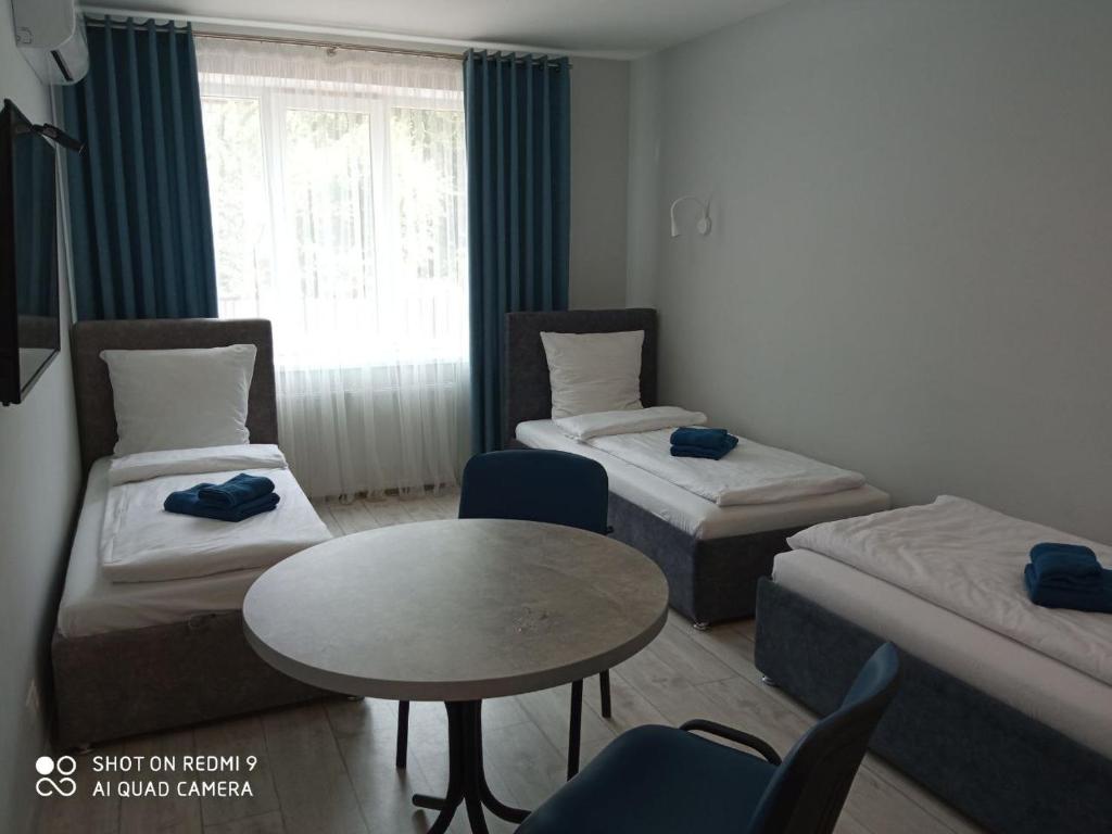 a small room with two beds and a table and chairs at HotelRoom 1 in Uzhhorod