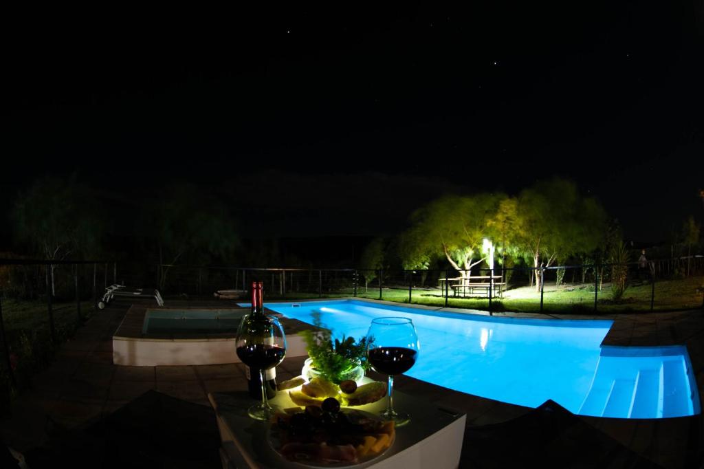 una mesa con copas de vino y un bol de fruta junto a la piscina en Cabañas La Emilia Apart en Valle Grande