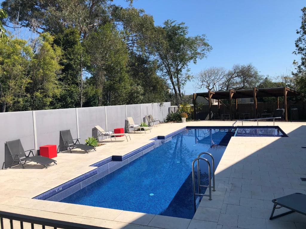 a large swimming pool with chairs and a fence at Hawks Nest Motel in Hawks Nest