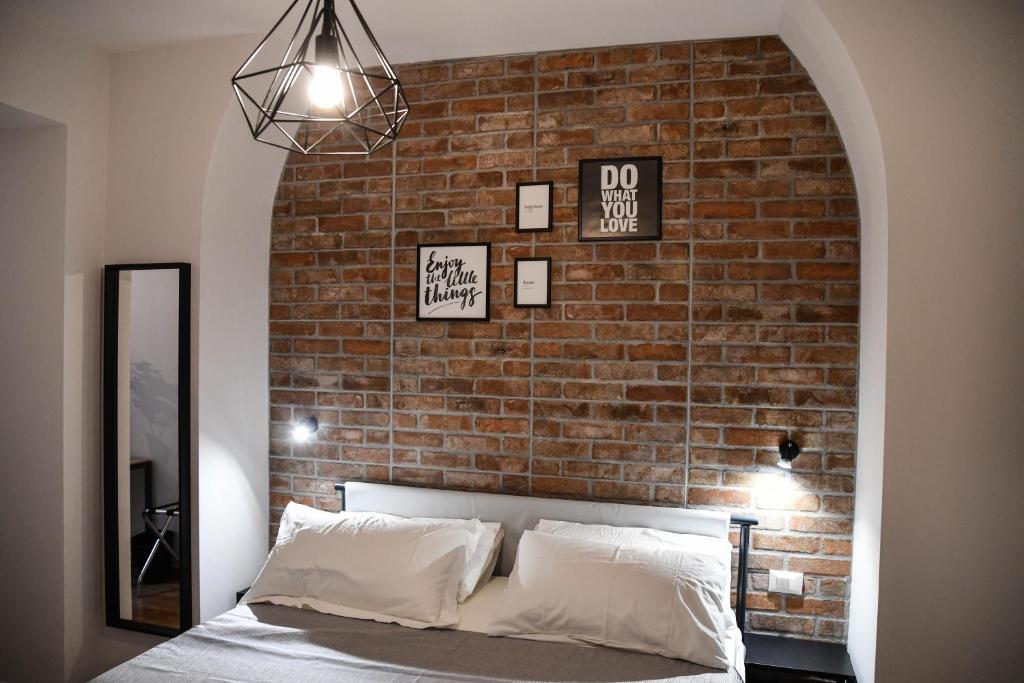 1 dormitorio con pared de ladrillo, cama y espejo en Urban Holiday, en Roma