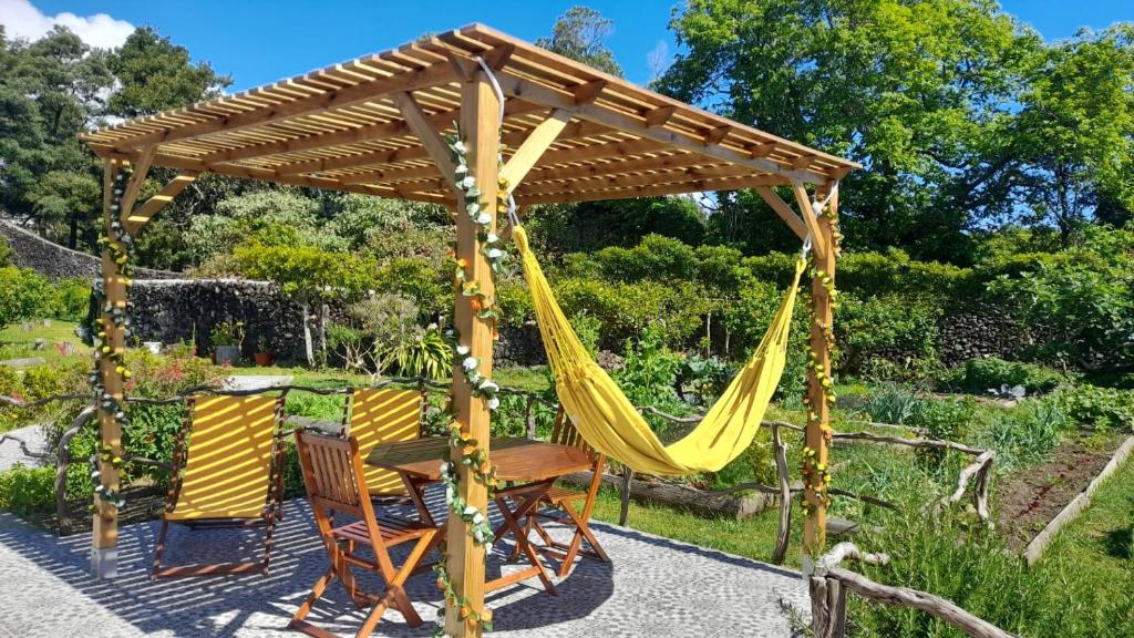 a hammock and chairs under a wooden pergola at Quinta dos Sentidos , Rustic Holiday Houses in São Vicente Ferreira in São Vicente Ferreira