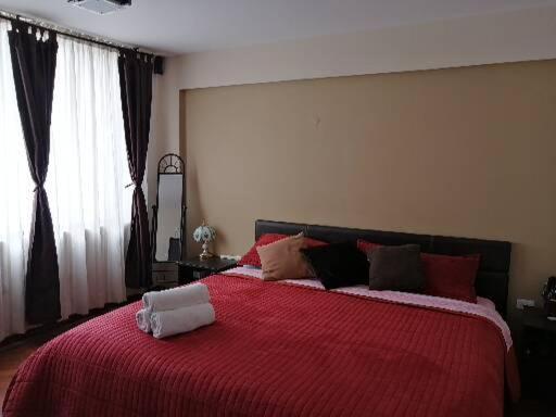 a bedroom with a large bed with a red blanket at FAKALI Homestay in Quito