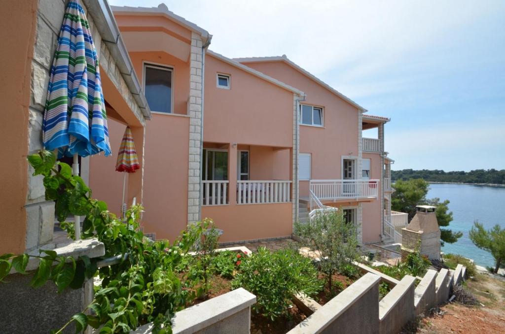 een huis met een paraplu naast een waterlichaam bij Apartment in Karbuni with sea view, terrace, air conditioning, W-LAN 3609-1 in Blato