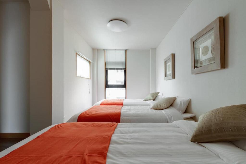 dwa łóżka w pokoju z biało-pomarańczowym w obiekcie KB1*Unique HUGE house for family /JR +subway w Osace