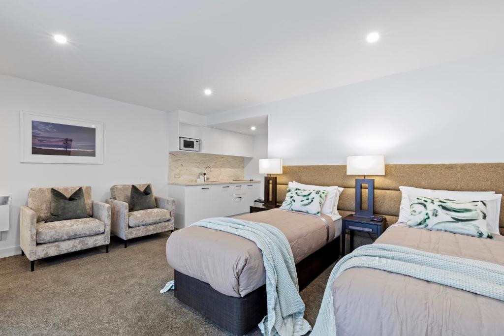 a bedroom with two beds and a chair at Queenstown House Lakeside in Queenstown