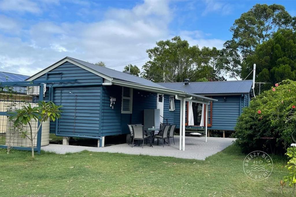 a blue house with a table and chairs in a yard at Breezy Blue on Bribie in Bongaree