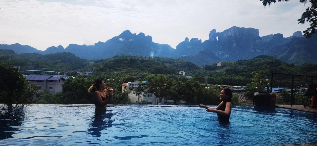 Dos mujeres en una piscina con montañas en el fondo en Tujia folk houses en Zhangjiajie