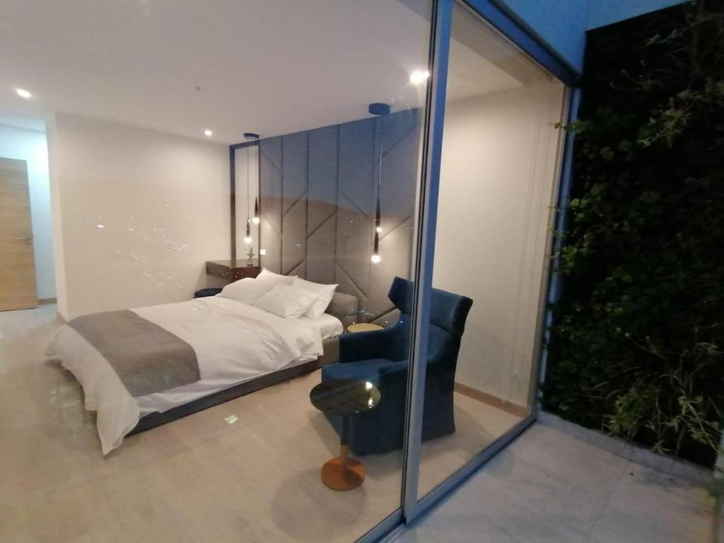 een slaapkamer met een bed, een stoel en een raam bij Suite Apartameto 1606 Espectacular Vista La Carolina, piso 16 ONE - Quito in Quito