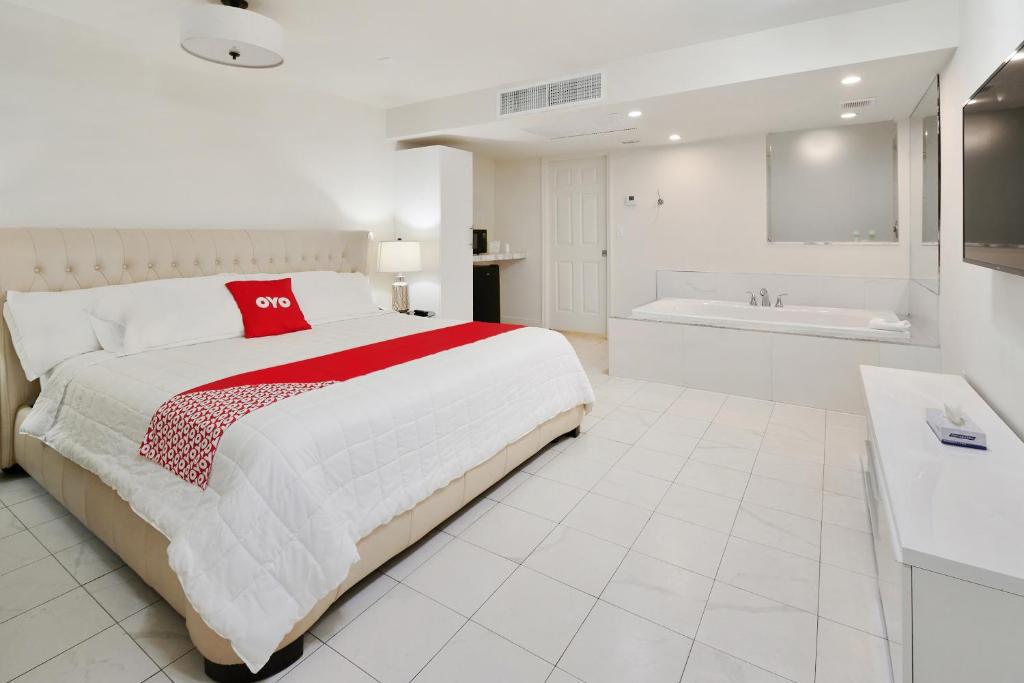 a white bedroom with a large bed and a bath tub at OYO Hotel Coral Gables - Miami Airport in Miami