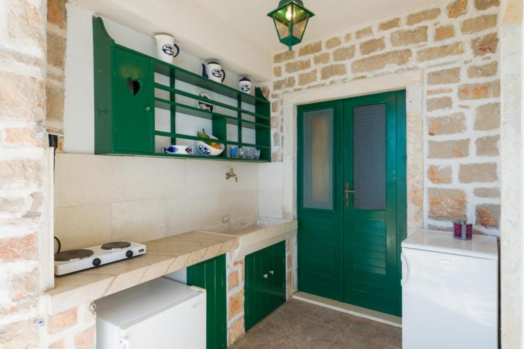 a kitchen with green cabinets and a green door at Vineyard Cottages - Murvica (146) in Murvica