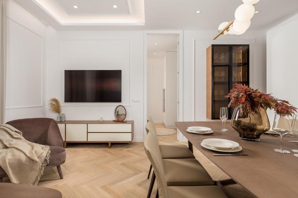 a dining room with a table and chairs and a television at Plaza Apartments in Opatija