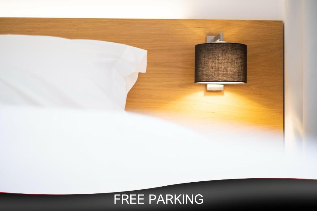 a bed with a free parking sign and a lamp at City Loft Hotel in Patra