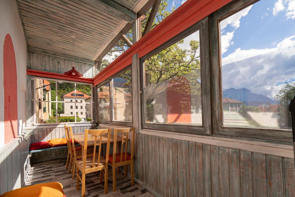 una veranda schermata con tavolo, sedie e finestre di Absteige Innsbruck- Zentrale Ferienapartments a Innsbruck