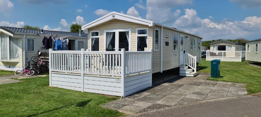 uma pequena casa branca com um alpendre e um portão em KMH Caravans at Flamingo Land em Kirby Misperton