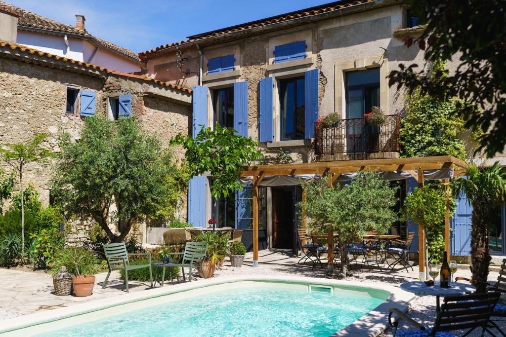 a villa with a swimming pool in front of a building at Logement Onze Chambres & Gîtes in Raissac-dʼAude