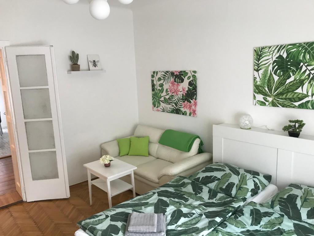 a bedroom with a bed and a couch and a mirror at Rosmarinus Apartman in Pécs