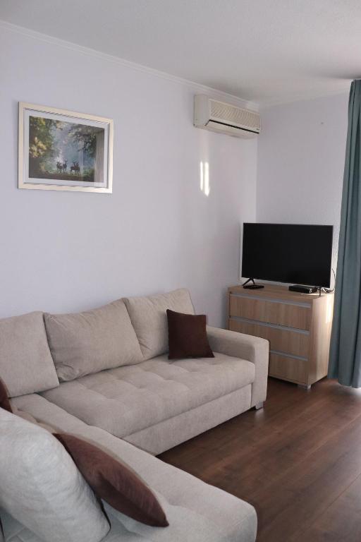 a living room with a couch and a flat screen tv at Liget Apartmanház in Kehidakustány